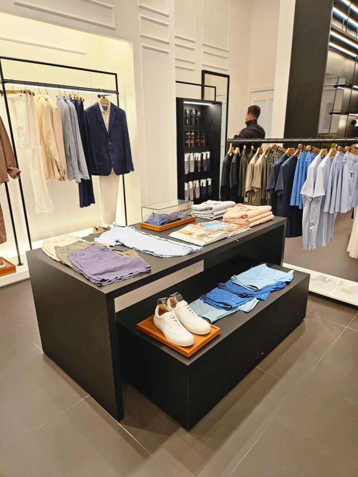 Home Contemporary clothing store showcasing tailored suits, casual shirts, and accessories.