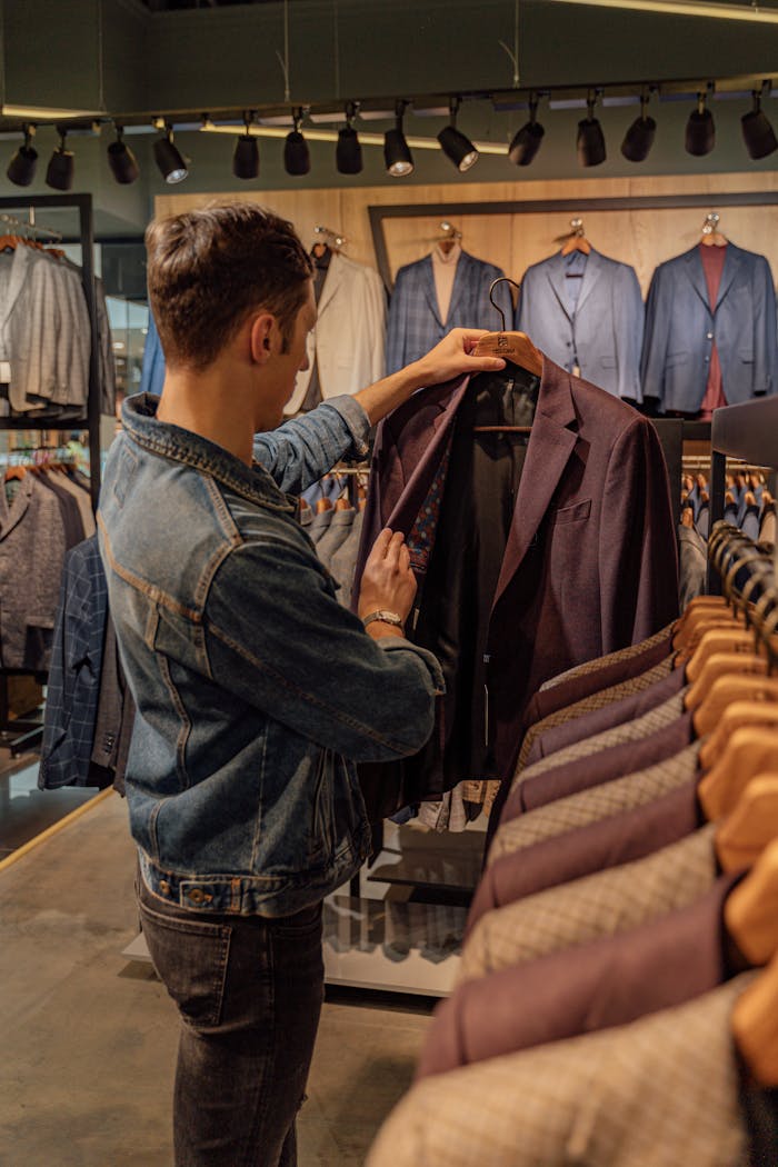 A man browsing through suits in a stylish clothing store, examining a jacket.